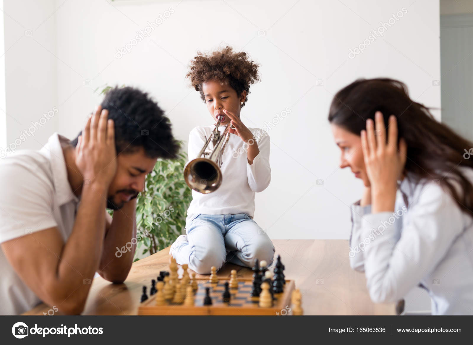 Mãe e pai tentando jogar xadrez enquanto seu filho toca trompete fotos,  imagens de © nd3000 #165063536